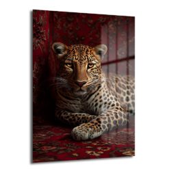 Kırmızı ve bordo tonlarında desenli bir halı üzerinde uzanmış, altın gözlü asil bir leopar portresi içeren dekoratif temperli cam tablo, modern salonlar için güçlü bir duvar dekorasyonu.