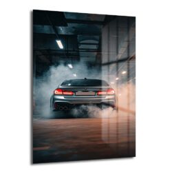 Arka planda dumanlar içinde, kırmızı stop lambaları yanan gümüş renkli bir BMW M5 otomobilin yer aldığı temperli cam tablo, modern ofis veya salon duvar dekorasyonu için ideal.