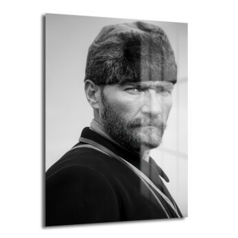 Siyah beyaz cam tablo, tüylü kalpaklı ve bıyıklı Mustafa Kemal Atatürk'ün güçlü ve kararlı bakışını yandan gösteren portresi.