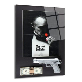 Siyah bir zemin üzerinde, The Godfather filminin ikonik afişinin yer aldığı, afişin altında gümüş renkli bir tabanca ve bir deste yüz dolarlık banknotların bulunduğu, parlak yüzeyli dikdörtgen cam tablo.