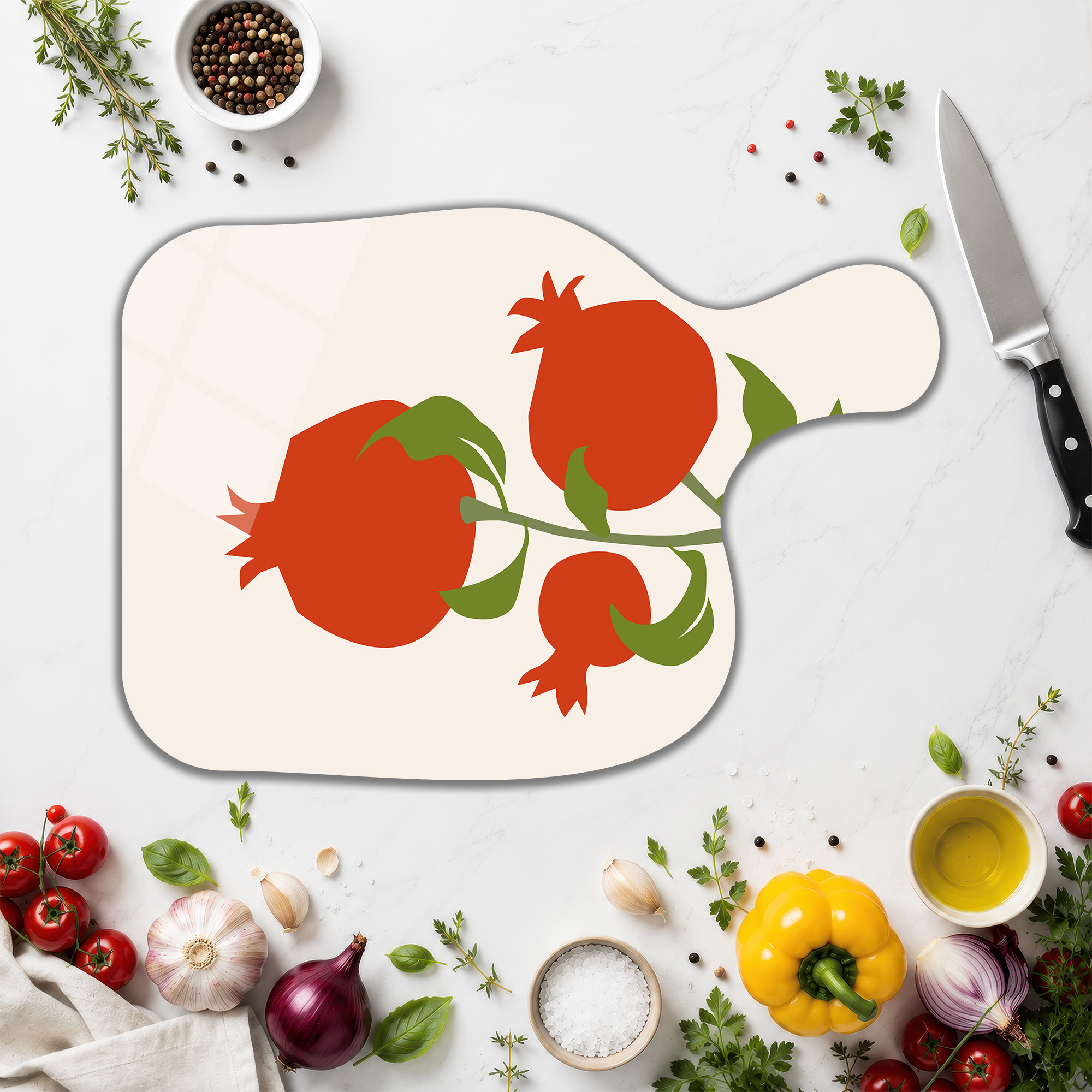 Minimalist Mutfak Tasarımı İçin Estetik ve Pratik Fikirler - Glazella Beyaz mermer tezgah üzerinde, nar desenli, kırmızı ve yeşil renklerde meyve motifli cam kesme tahtası, etrafında taze sebzeler, baharatlar ve bir şef bıçağı bulunuyor.